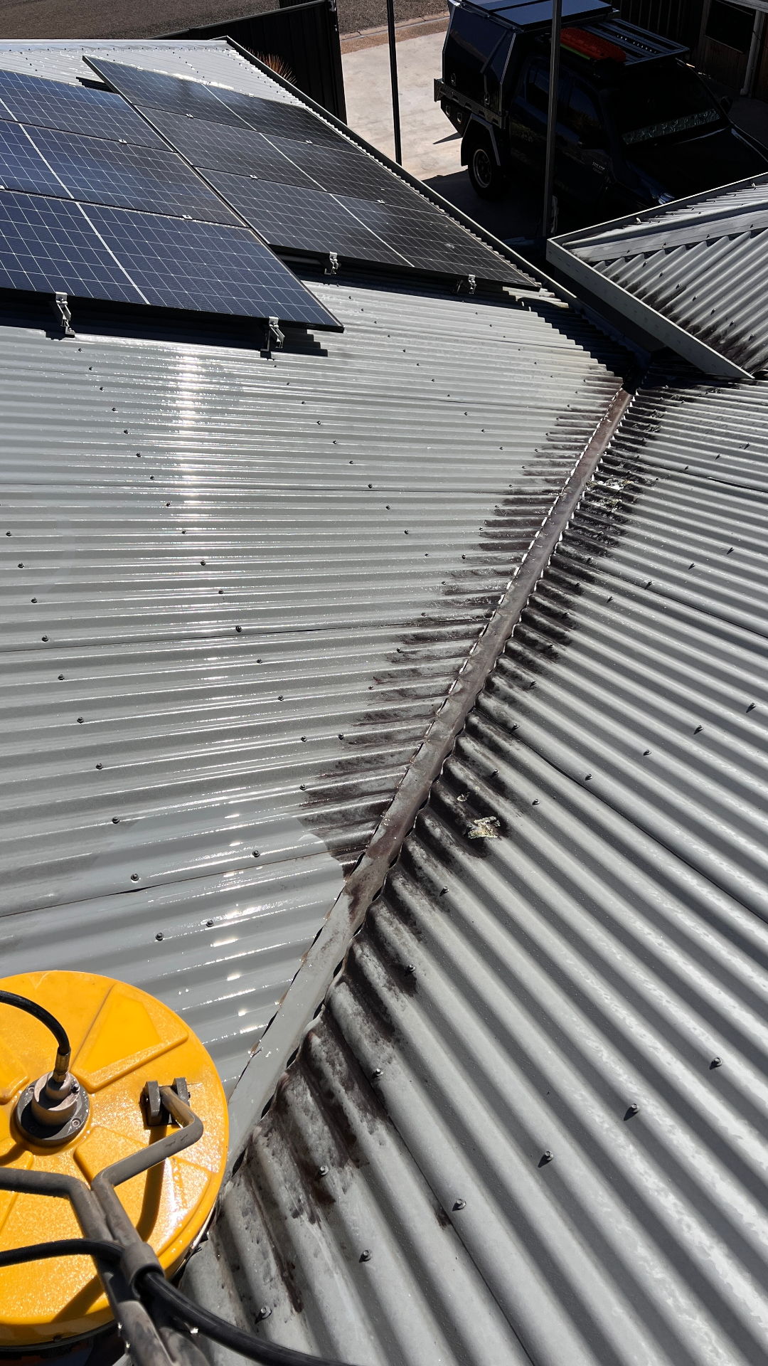 Surface cleaner mid-clean on commercial corrugated roof valley